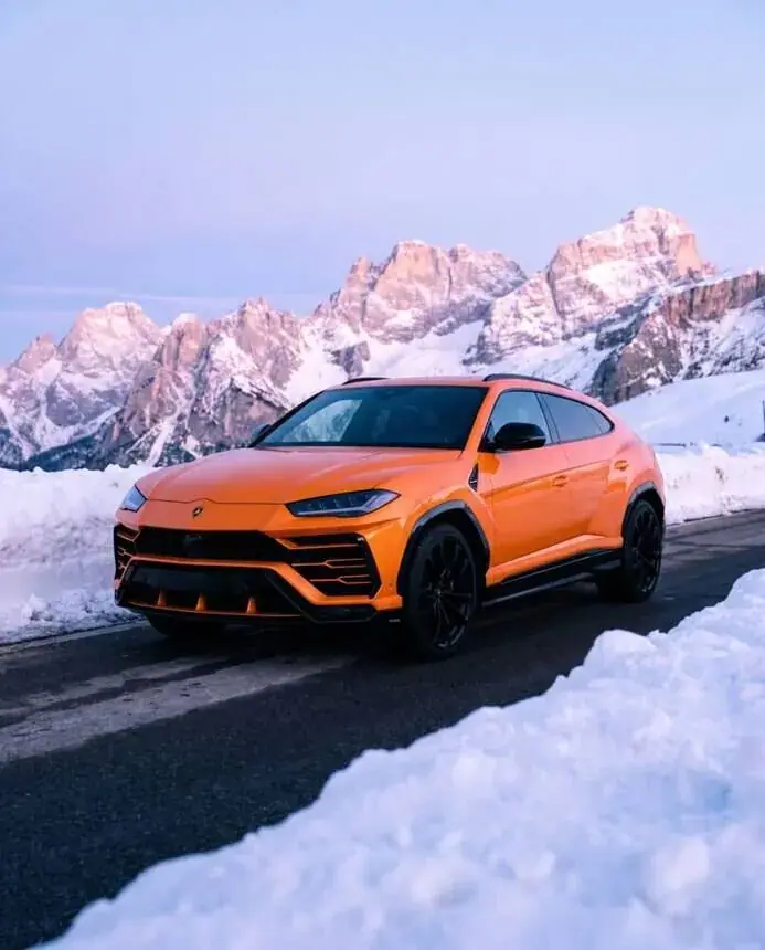 Automotive campaign frame: orange SUV in snow, mountains