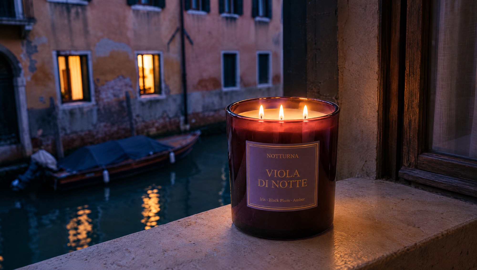 The same candle on a stone window sill above a Venetian canal at blue hour