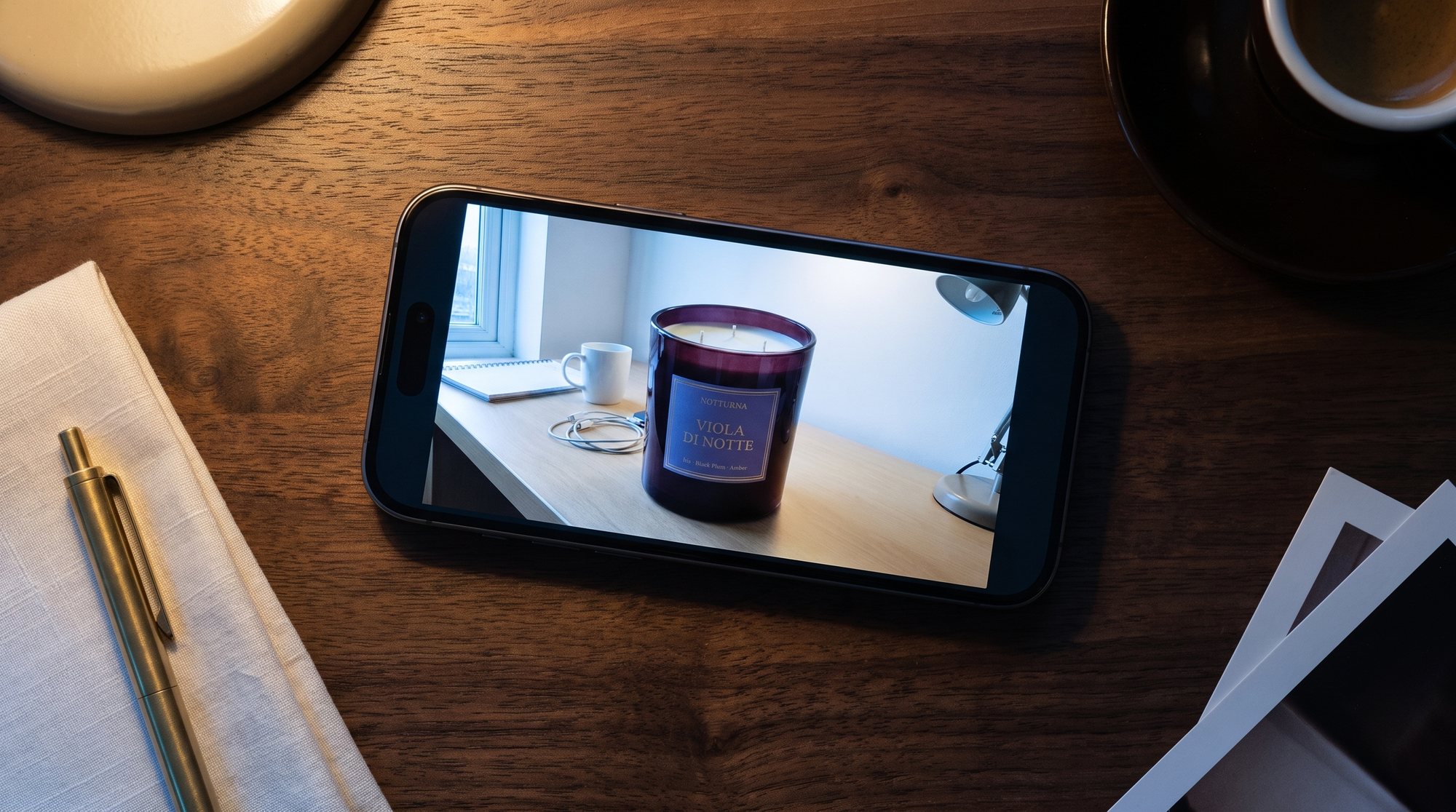 A phone on a table showing the client's own photo of a plum glass candle
