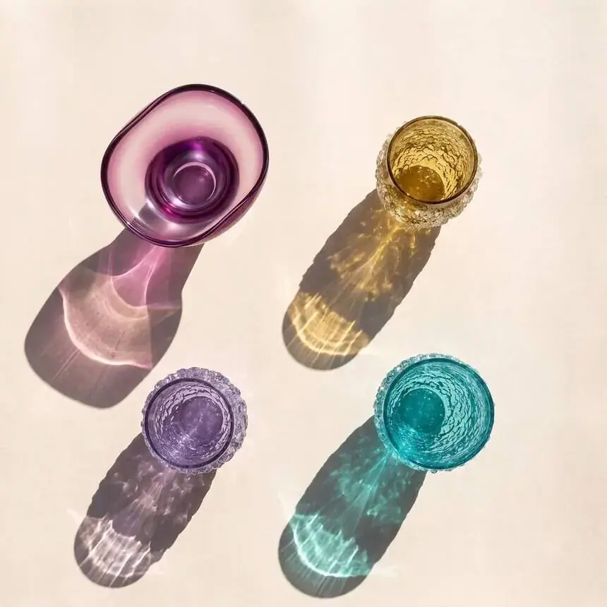 Product photos for design brands: coloured Murano glasses casting shadows on linen